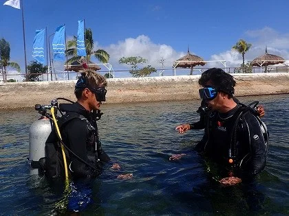 浅い海でダイビング機材の使い方を教わる講習参加者