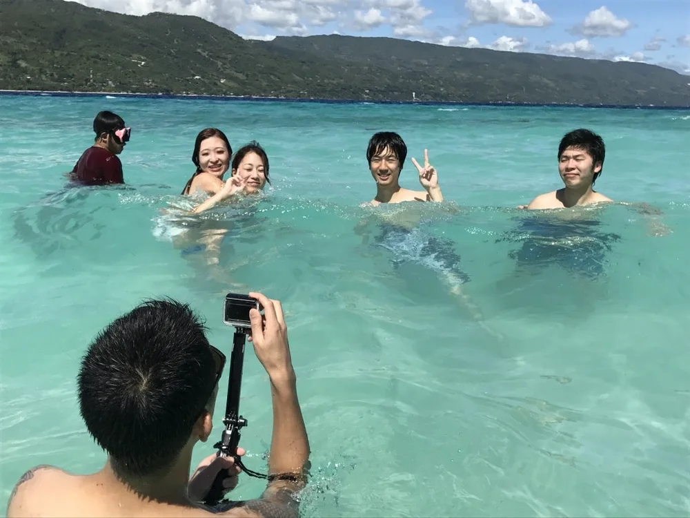 透き通るスミロン島の海で参加者の記念写真を撮影する様子
